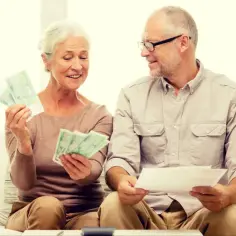 Uśmiechnięci seniorzy liczą pieniądze, być może planując wydatki z programu 500 plus dla seniora.