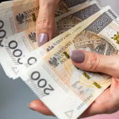 Dłonie trzymają stos banknotów 200 złotych. To jakby dekret na lepsze jutro, obietnica spełnienia marzeń.