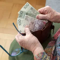 Dłoń emerytki liczy banknoty 100 i 20 zł. To może być kwota po drugiej waloryzacji emerytur.