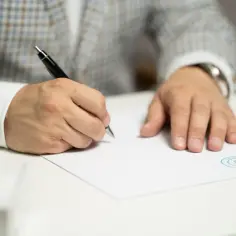 Mężczyzna w eleganckim garniturze podpisuje dokument. Czy umowa zlecenie wlicza się do emerytury? To pytanie nurtuje wielu pracujących.