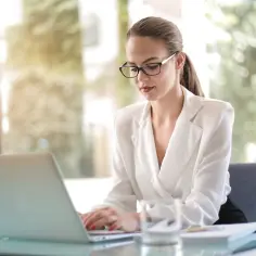 Kobieta w okularach pracuje przy laptopie, planując swoją działalność nierejestrowaną w 2025 roku.