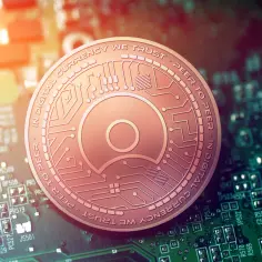 Miedziany token z napisem "IN DIGITAL CURRENCY WE TRUST - PEER TO PEER" leży na zielonej płytce drukowanej.