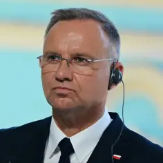 Prezydent w okularach i słuchawkach, z wpiętą flagą Polski. Myśli o przyszłości, może o swojej emeryturze prezydenckiej.