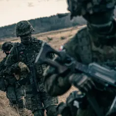 Żołnierze w kamuflażu maszerują przez pole. Zastanawiasz się, ile zarabia podporucznik?