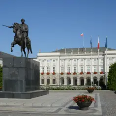 Pałac Prezydencki, gdzie mieszka prezydent Polski, z pomnikiem konnym i polską flagą.