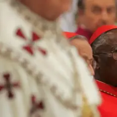 Kardynał w czerwonej piusce i okularach, obok niego duchowny w białej szacie z krzyżami. Czyżby to był czarny papież?