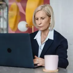 Kobieta w garniturze pracuje przy laptopie, myśląc o dodatku do wynagrodzenia.
