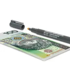 Banknot 100 zł obok pisaka do wykrywania fałszerstw. Pisak z napisem "COUNTERFEIT MONEY DETECTOR" sugeruje, że zaraz sprawdzimy autentyczność banknotu.