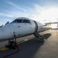 Samolot LOT Polish Airlines z otwartymi schodkami. W tle widać kolejny samolot. Pilot samolotu czeka na pasażerów.