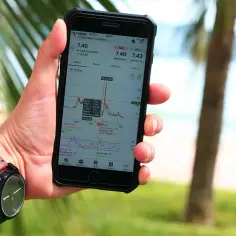 Ręka trzyma smartfon z wykresem akcji. Analiza danych finansowych, inwestycje, a może właśnie zastanawiasz się, capex co to jest?