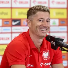 Uśmiechnięty Robert Lewandowski w czerwonej koszulce reprezentacji Polski, siedzi przy mikrofonie. Ile języków zna Robert Lewandowski?