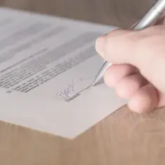 Dłoń podpisuje dokument, finalizując umowę NDA.