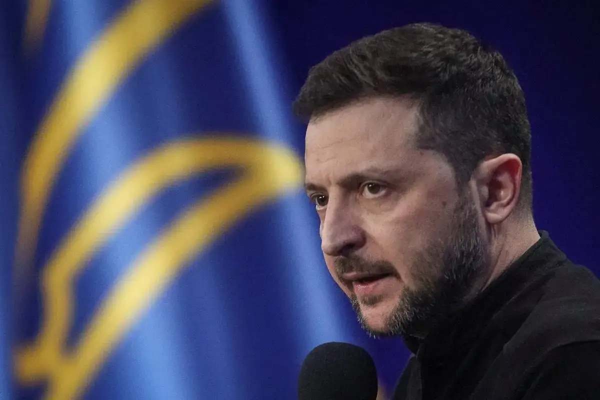 Prezydent Ukrainy Wołodymyr Zełenski przemawia na tle flagi swojego kraju.