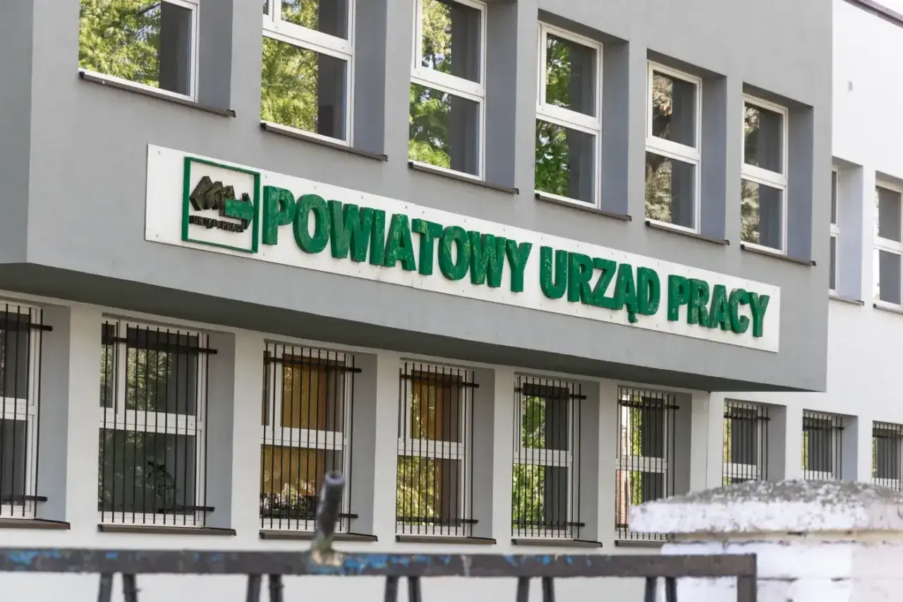 Powiatowy Urząd Pracy, gdzie wielu szuka wsparcia i nowych możliwości. Budynek z zielonym napisem i kratami w oknach.
